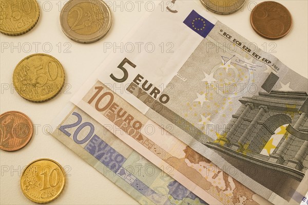 Close-up of five, ten, twenty Euro bank notes and assorted 2, 5, 10, 50 cent coins on white