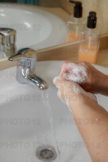 Closeup of a woman washing her hands with liquid soap suds in the bathroom sink. Hand hygiene from