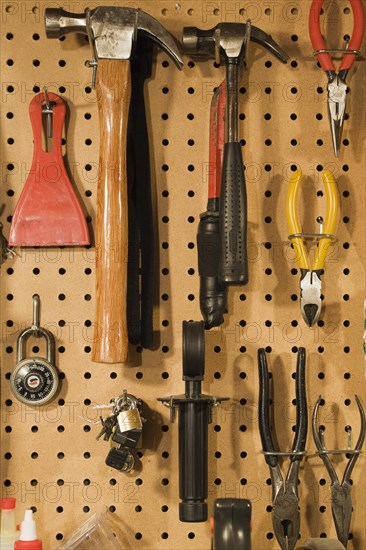 Assorted hand tools that include a small and medium hammer, red needle nose pliers, yellow wire