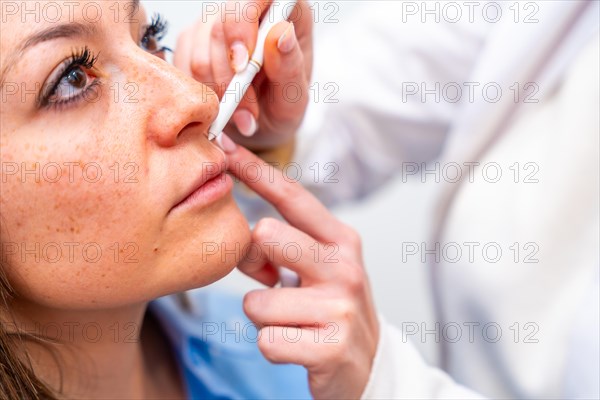 Close-up of the hands of a cosmetologist marking the points to inject hyaluronic acid on the
