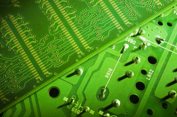 Close-up of fluorescent green lighted electronic computer circuit boards with silver solder points