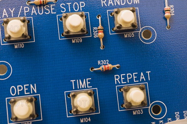 Close-up of blue electronic DVD player circuit board with function push button controls, Studio