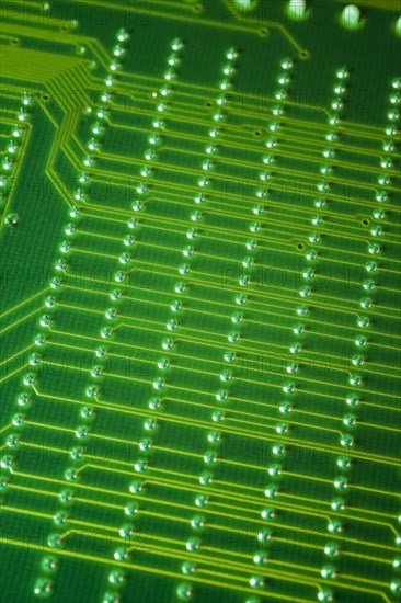 Close-up of fluorescent green lighted electronic computer circuit board with lines and silver