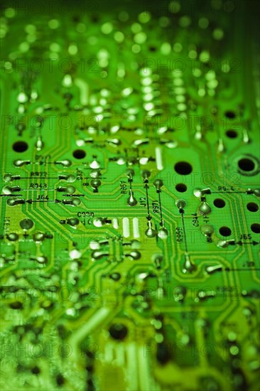 Close-up of green lighted electronic computer circuit board with silver solder points and lines,