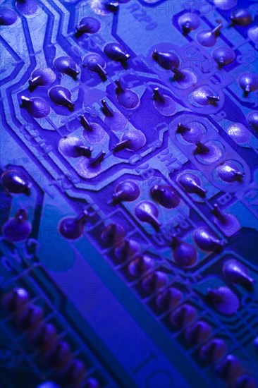 Close-up of blue purple lighted electronic computer circuit board with silver solder points, Studio