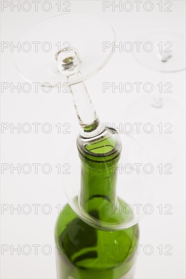 Close-up of upside down wine glass on top of consumed and empty red wine bottle, Studio