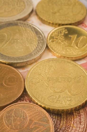 Close-up of gold and copper colored assorted five, ten, fifty Euro cent coins on top of Euro bank