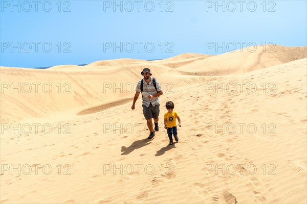 Father and son on vacation laughing running in the dunes of Maspalomas, Gran Canaria, Canary