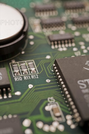 Close-ip of green computer circuit board with hard disc, memory chip, silver solder points and