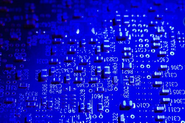 Close-up of blue lighted electronic computer circuit board with white numbers and letters, Studio
