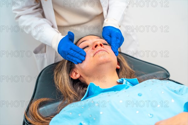 Aesthetic female doctor applying numbing cream on the face of a woman before injecting hyaluronic
