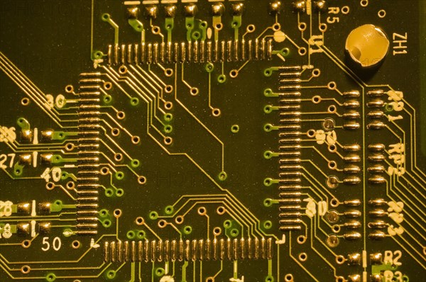 Close-up of microchip, silver solder points and lines on golden lighted electronic computer circuit