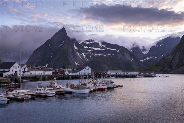 The village of Hamnoy. Houses and boats in a small harbour. Mount Olstinden in the background. At