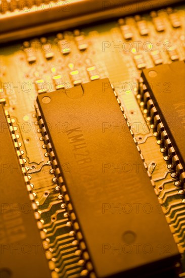 Close-up of orange yellow lighted electronic computer circuit board with memory chips and silver