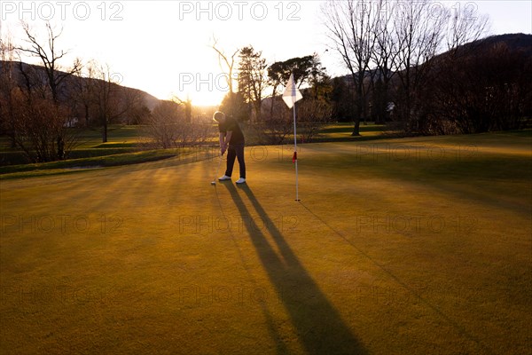 Male Golfer Concentration on the Putting Green on Golf Course in Sunset with Shadow in Switzerland.