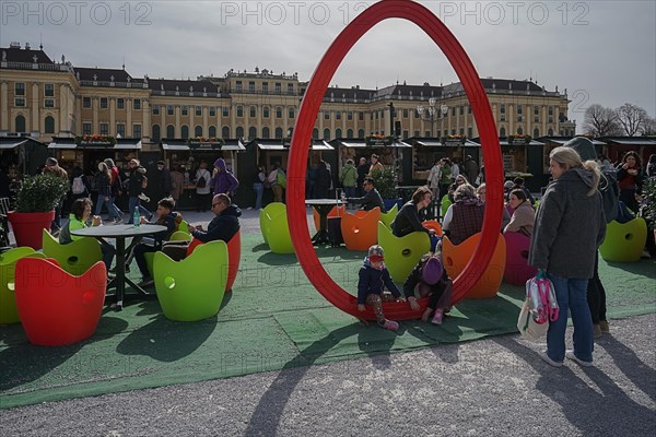 Lively Easter market with children and adults sitting on colourful apple chairs, with a large red