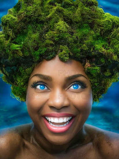A woman with a vibrant smile and green moss hair submerged in blue water, earth day concept, AI