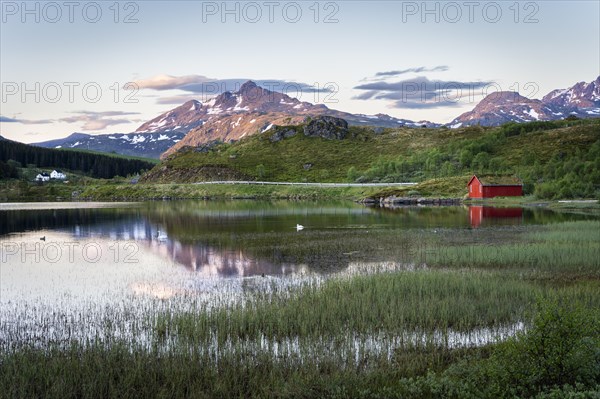 Landscape in the Lofoten Islands. Lake Holdalsvatnet with vegetation on the shore. A red wooden