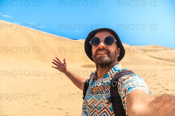 Selfie of a tourist with glasses and hat enjoying in the dunes of Maspalomas, Gran Canaria, Canary