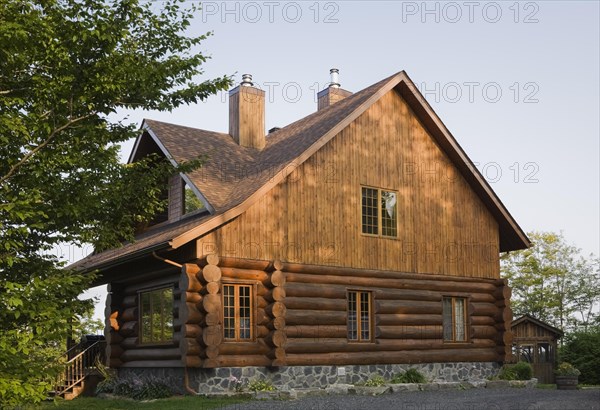 Facade and side view of rustic contemporary Scandinavian hybrid style log cabin home with light