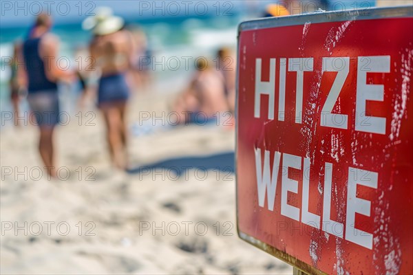 Warning sign with German text 'Hitzewelle' (Heat wave) in front of blurry sunny beach with people.