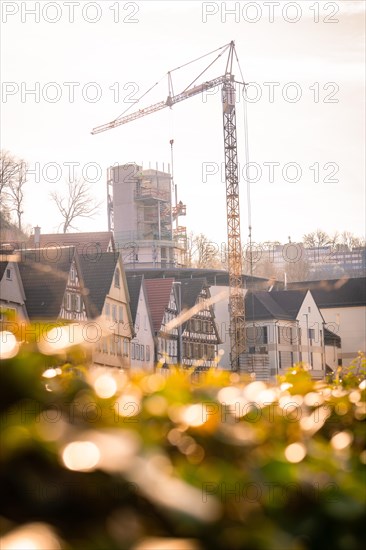 A construction crane towers over a building site against the backdrop of old half-timbered houses,