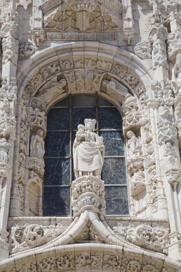 Arched window decorated with carved sculptures on facade of Jeronimos Monastery, Lisbon, Portugal,