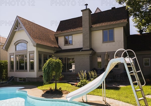 Rear view of a grey brick and cream cladding with grey trim contemporary cottage style home and
