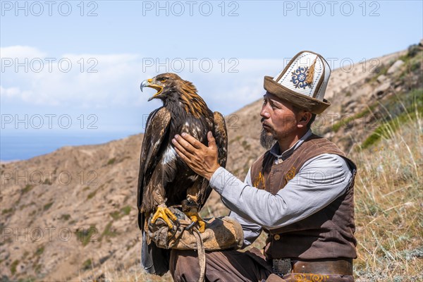 Traditional Kyrgyz eagle hunter with eagle in the mountains, hunting, near Bokonbayevo, Issyk Kul