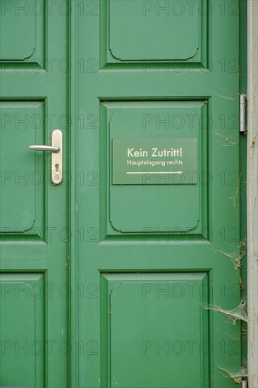 No entry, main entrance on the right, sign on a green front door in the historic city centre of