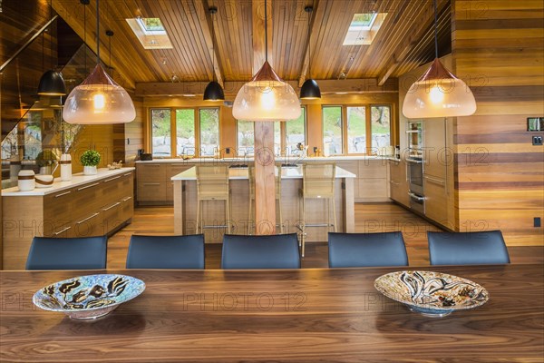 Illuminated industrial style copper with frosted glass pendant lighting fixtures over wooden dining