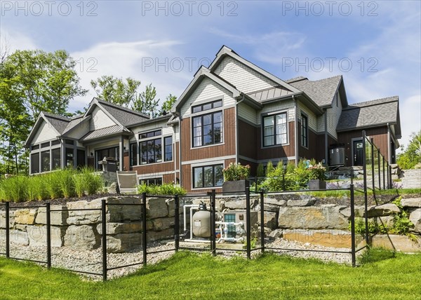 Rear view of contemporary natural stone and brown stained wood and cedar shingles clad luxurious
