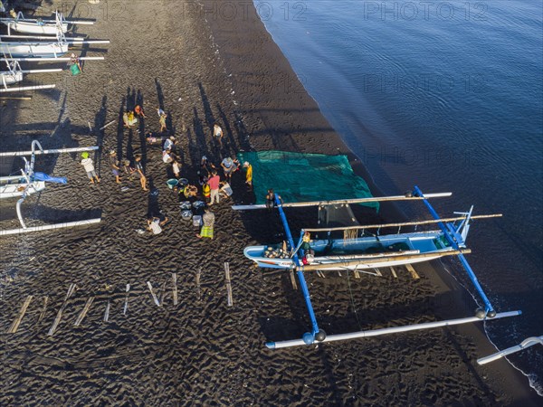 Fishermen unload their catch from their outrigger boat in the morning. Amed, Karangasem, Bali,
