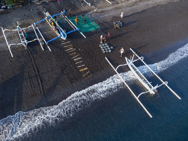 Fishermen unload their catch from their outrigger boat in the morning. Amed, Karangasem, Bali,