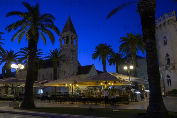 Outdoor restaurant at night with historic church tower and palm trees, Trogir, Dalmatia, Croatia,