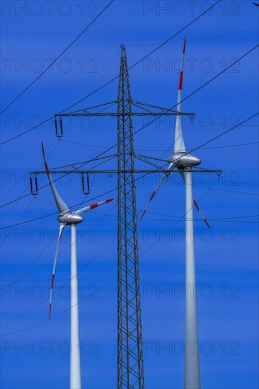 Power pylon with high-voltage lines and wind turbines at the Avacon substation Helmstedt,