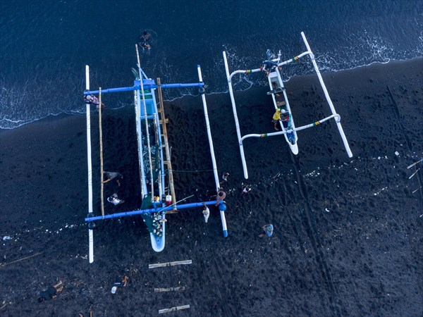 Fishermen unload their catch from their outrigger boat in the morning. Amed, Karangasem, Bali,