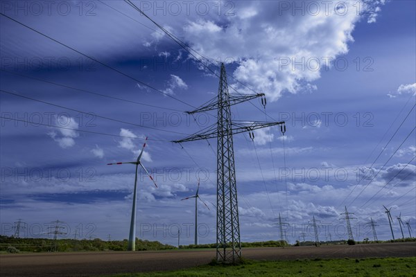 Power pylons with high-voltage lines and wind turbines at the Avacon substation in Helmstedt,