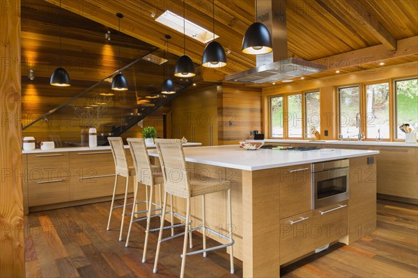 Bamboo wood island with white quartz countertops and high wicker chairs, buffet in kitchen with Ipe