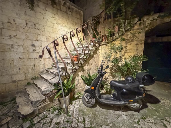 An old staircase with an abandoned scooter in a nocturnal setting, Trogir, Dalmatia, Croatia,