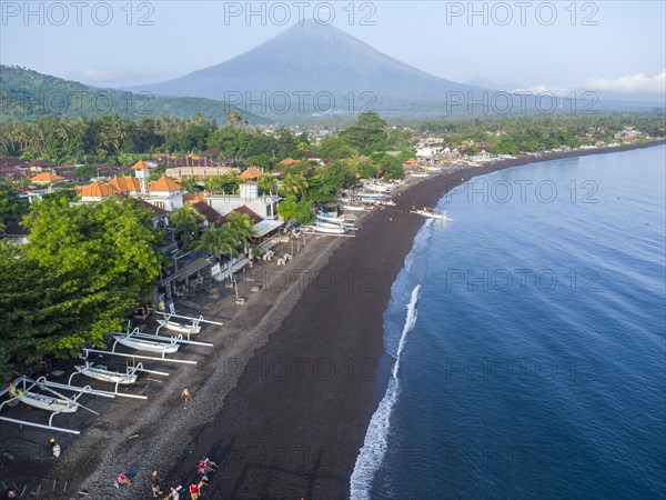 Fishermen unload their catch from their outrigger boat in the morning, in the background Gunung