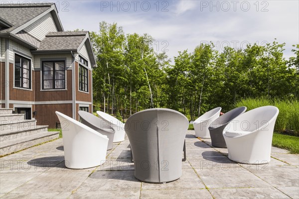 White and grey cloth covered sitting chairs on backyard patio and rear view of contemporary natural