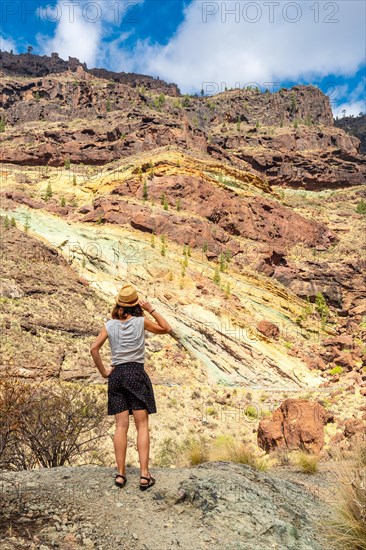 A woman with a hat at the Natural Monument Azulejos de Veneguera or Rainbow Rocks in Mogan, Gran