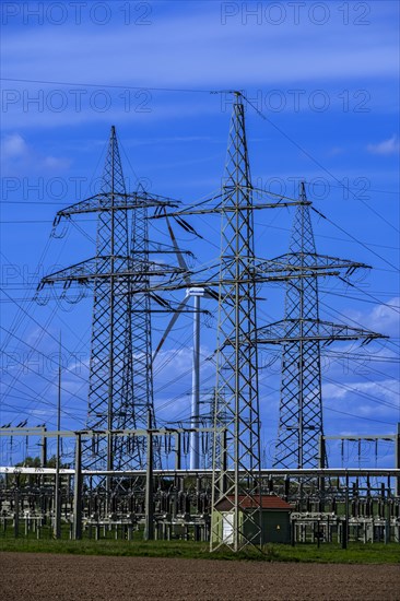 Power pylons with high-voltage lines and wind turbine at the Avacon substation in Helmstedt,