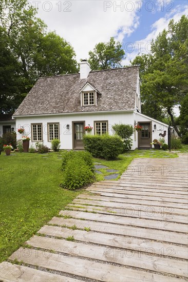 Old circa 1886 white with beige and brown trim Canadiana cottage style home facade and wood plank