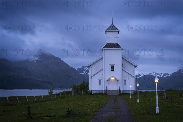 The white church of Gimsoy (Gimsoysand church) by the sea. A path leads to the church. The church
