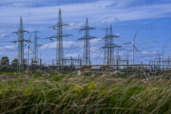 Power pylons with high-voltage lines and wind turbines at the Avacon substation in Helmstedt,