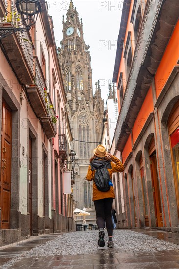 A tourist woman with a hat walking along a beautiful street next to the Church of San Juan