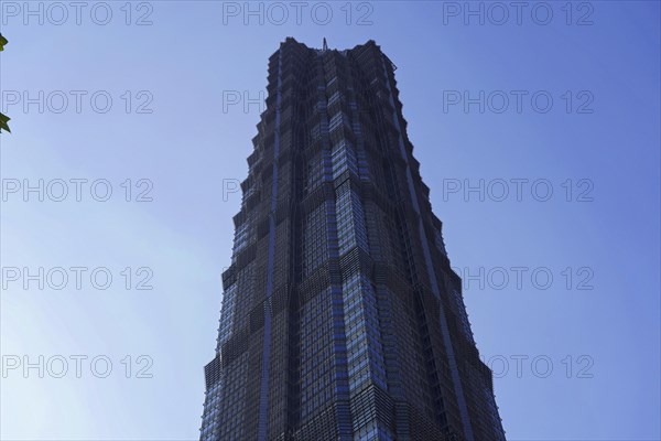 The facade of a geometrically designed skyscraper stands out against the blue sky, Shanghai, China,