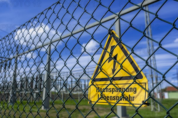 Yellow warning sign with the inscription Hochspannung Lebensgefahr! on a fence of the Avacon